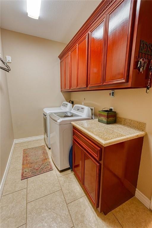 washroom featuring light tile patterned flooring, cabinet space, independent washer and dryer, and baseboards