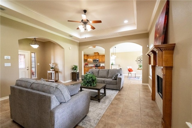 14426 Pentridge Dr, Corpus Christi, TX 78410 - living area with a ceiling fan, a raised ceiling, crown molding, a fireplace, and light tile patterned floors