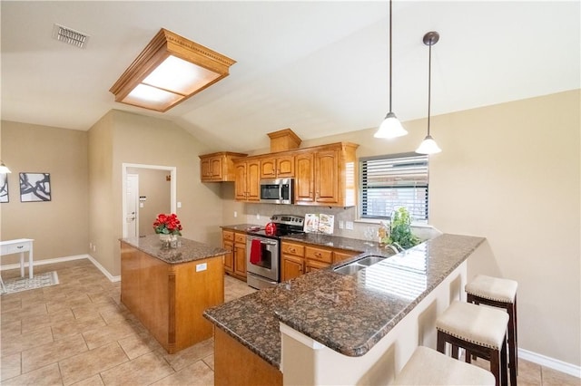 14426 Pentridge Dr, Corpus Christi, TX 78410 - kitchen featuring appliances with stainless steel finishes, vaulted ceiling, brown cabinetry, a center island, and dark stone counters
