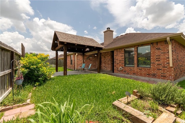 14426 Pentridge Dr, Corpus Christi, TX 78410 - back of house featuring brick siding, a fenced backyard, a chimney, a patio area, and roof with shingles