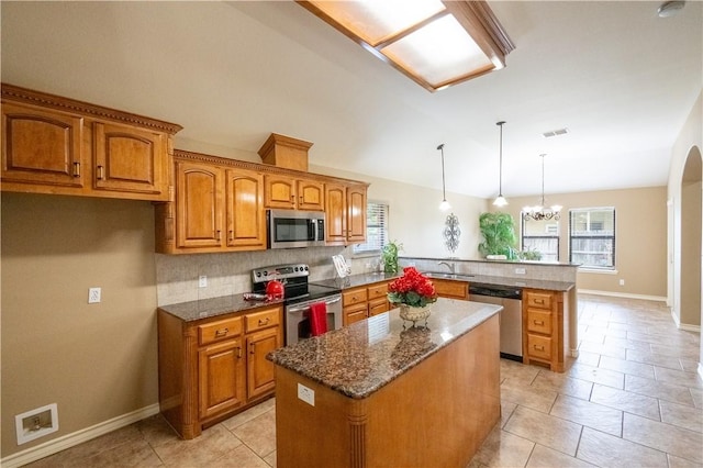 14426 Pentridge Dr, Corpus Christi, TX 78410 - kitchen with appliances with stainless steel finishes, a peninsula, brown cabinetry, plenty of natural light, and vaulted ceiling