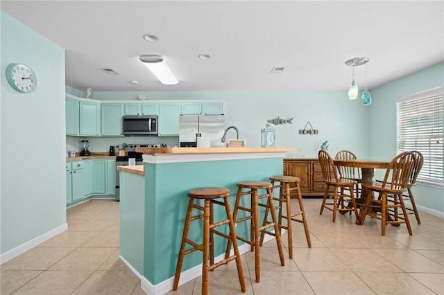 kitchen with light tile patterned flooring, visible vents, light countertops, appliances with stainless steel finishes, and decorative light fixtures