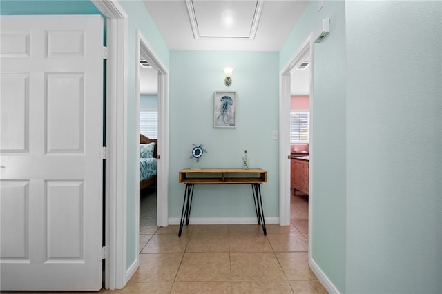 corridor featuring light tile patterned flooring and baseboards