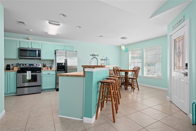 kitchen with light tile patterned floors, visible vents, appliances with stainless steel finishes, light countertops, and pendant lighting