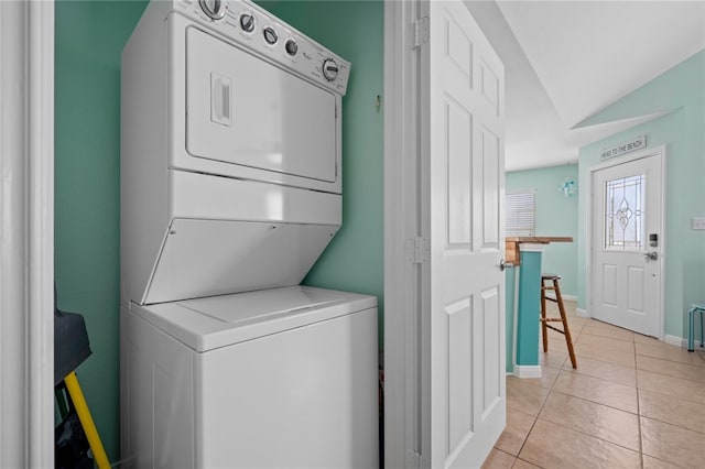 clothes washing area with light tile patterned floors, laundry area, baseboards, and stacked washer / dryer