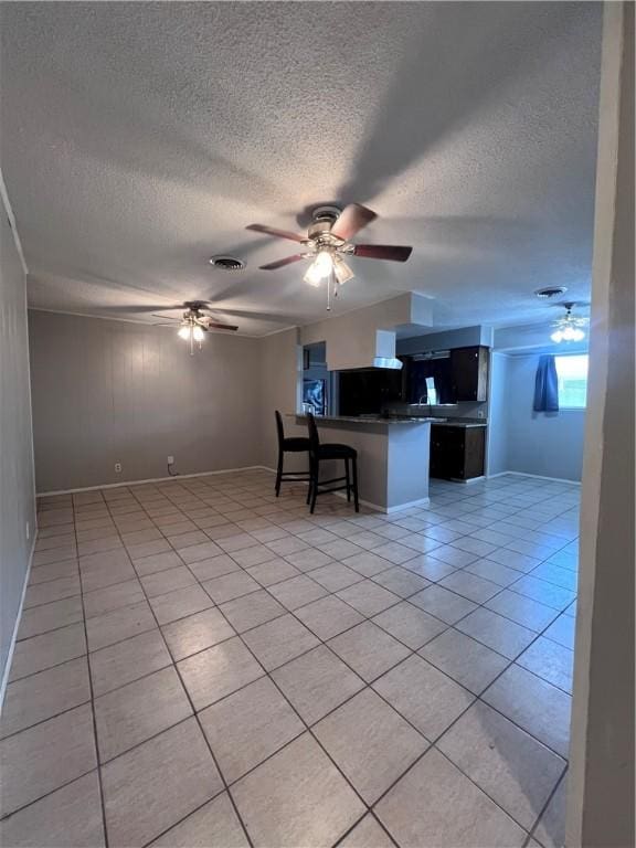 5825 San Saba Dr, Corpus Christi, TX 78407 - unfurnished living room with a textured ceiling, light tile patterned floors, and a ceiling fan
