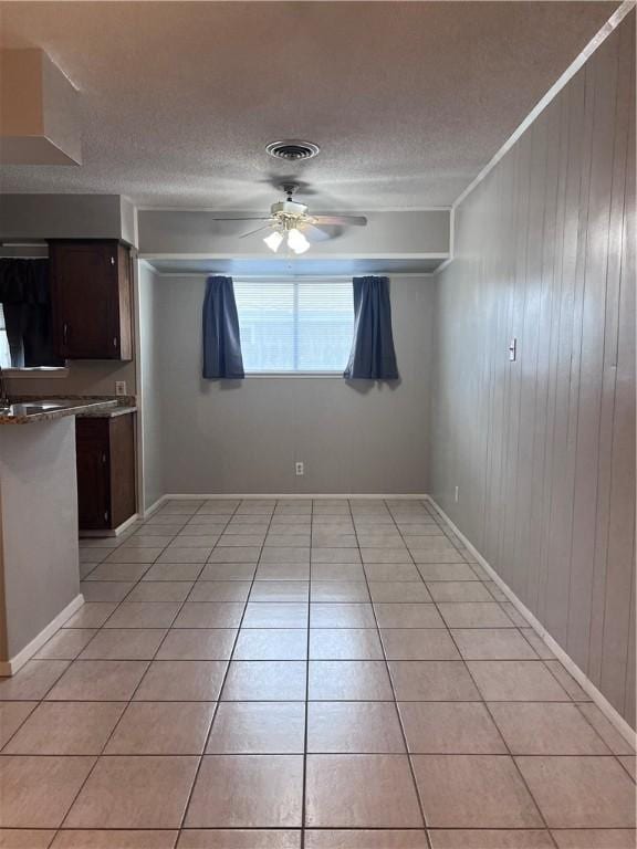 5825 San Saba Dr, Corpus Christi, TX 78407 - unfurnished dining area featuring ceiling fan, light tile patterned flooring, a textured ceiling, and wooden walls