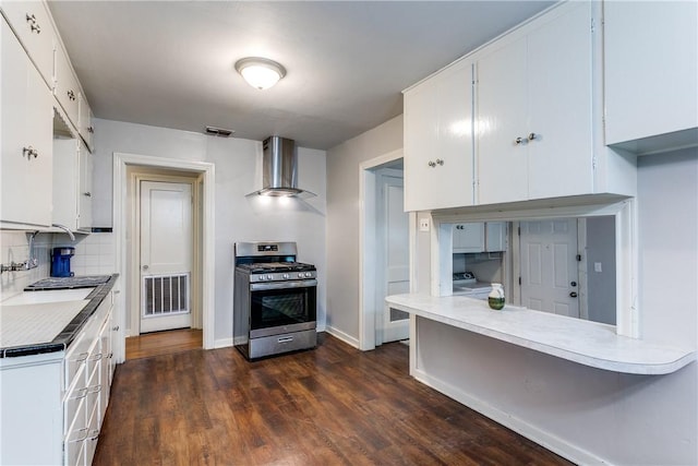 150 E Southcross Blvd, San Antonio, TX 78214 - kitchen featuring gas range, wall chimney exhaust hood, light countertops, dark wood finished floors, and white cabinetry