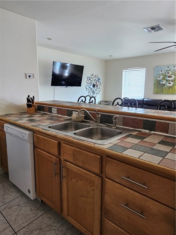 kitchen with white dishwasher, tile countertops, and sink