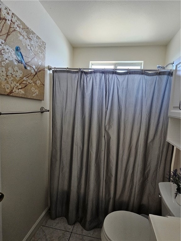 bathroom featuring toilet, shower / bath combo with shower curtain, and tile patterned floors