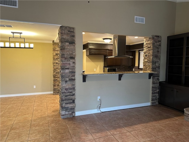 kitchen featuring ornamental molding, ornate columns, kitchen peninsula, and exhaust hood