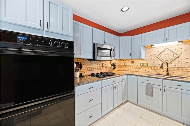 kitchen featuring a sink, decorative backsplash, light stone countertops, and black appliances