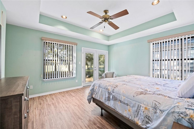 bedroom with access to exterior, baseboards, and a tray ceiling