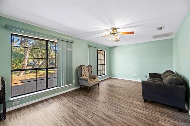 living area featuring visible vents, ceiling fan, baseboards, and wood finished floors