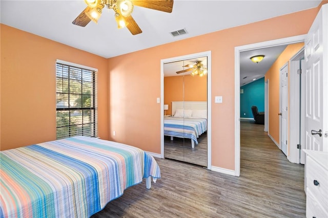 bedroom with ceiling fan, wood finished floors, visible vents, and baseboards