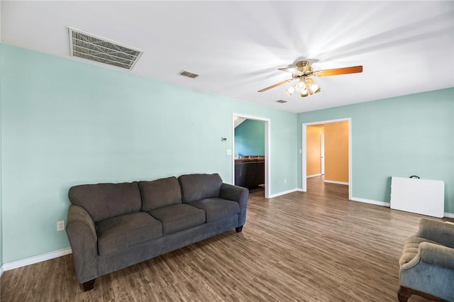 living room featuring visible vents, baseboards, and wood finished floors