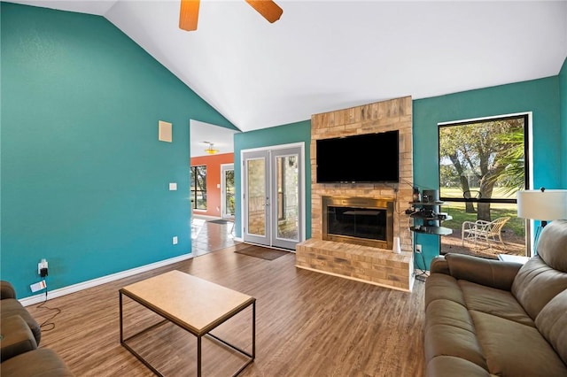 living area featuring french doors, baseboards, a brick fireplace, and wood finished floors