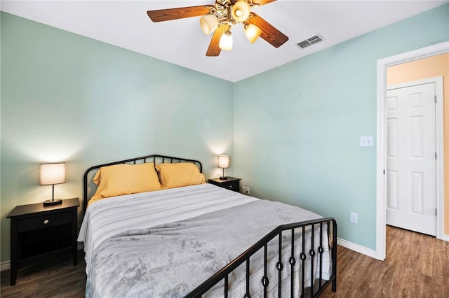 bedroom with ceiling fan, wood finished floors, visible vents, and baseboards