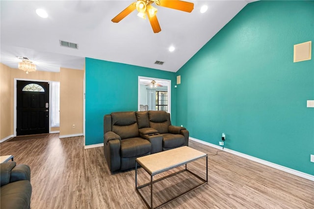 living area with vaulted ceiling, wood finished floors, visible vents, and baseboards