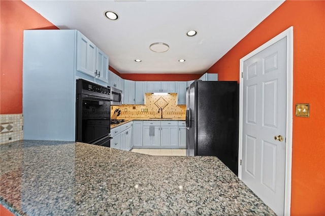 kitchen featuring stone counters, a sink, black appliances, and decorative backsplash