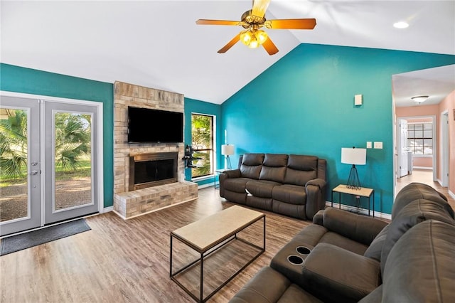 living area featuring ceiling fan, baseboards, vaulted ceiling, a fireplace, and wood finished floors