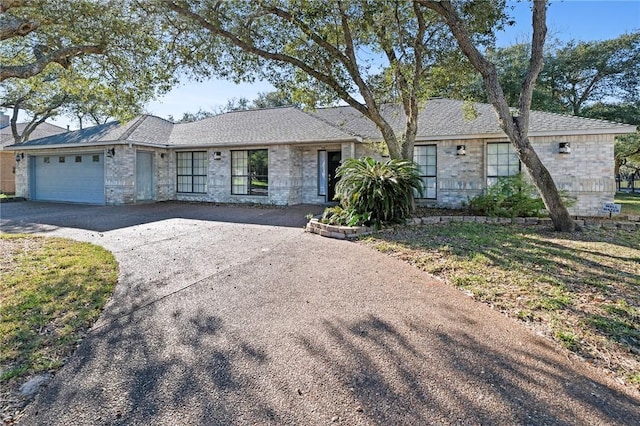 ranch-style house featuring aphalt driveway, an attached garage, and roof with shingles