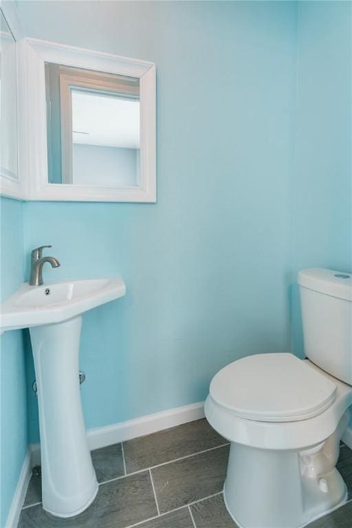 half bathroom featuring a sink, toilet, and baseboards