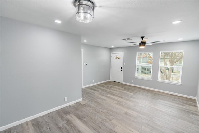 empty room with light wood-style floors, visible vents, and baseboards