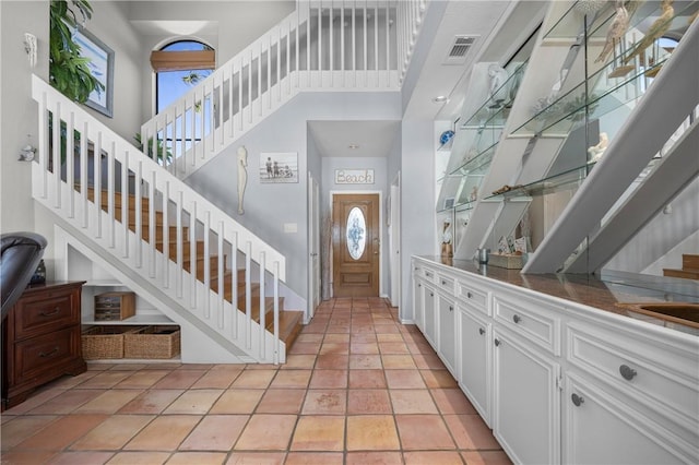 entryway featuring visible vents, a high ceiling, light tile patterned flooring, and stairs