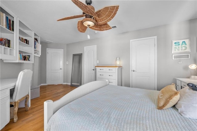 bedroom featuring baseboards, built in study area, light wood-style floors, and a ceiling fan