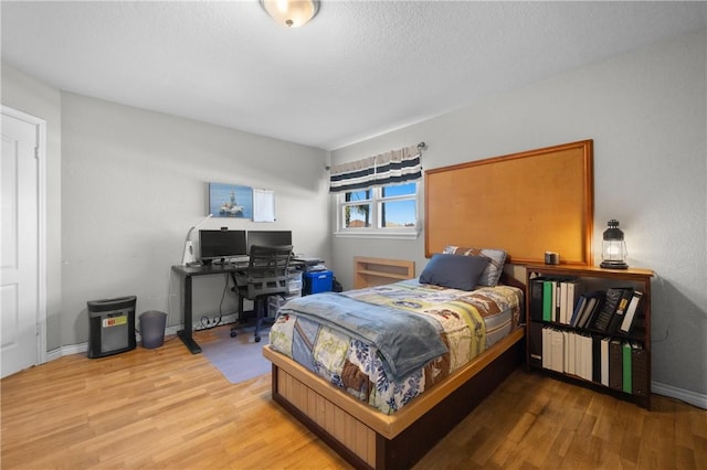 bedroom featuring wood finished floors, baseboards, and a textured ceiling