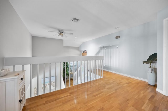 hallway with visible vents, baseboards, light wood-type flooring, lofted ceiling, and recessed lighting