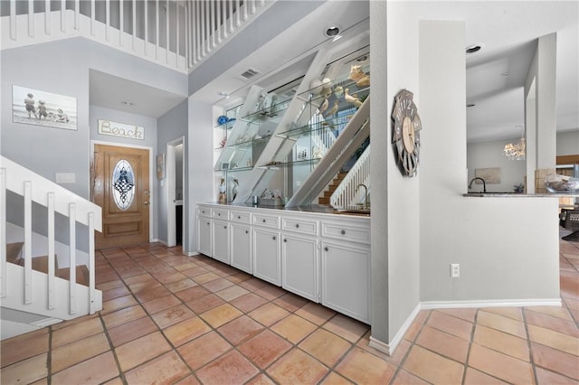 bar featuring light tile patterned floors, baseboards, visible vents, and a towering ceiling