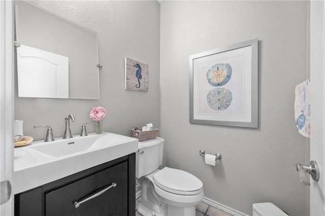 bathroom with toilet, vanity, and baseboards