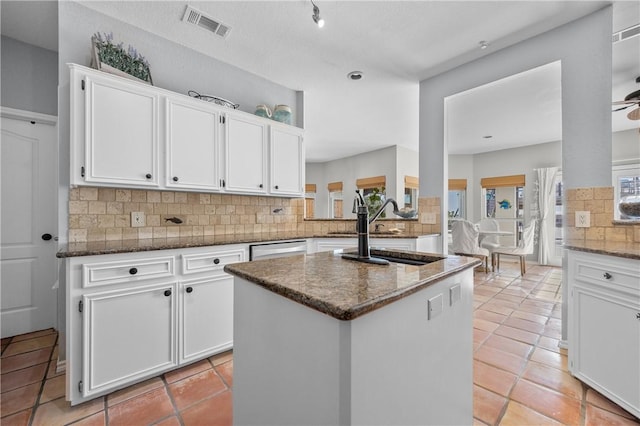 kitchen featuring visible vents, a sink, dark stone countertops, backsplash, and white cabinetry