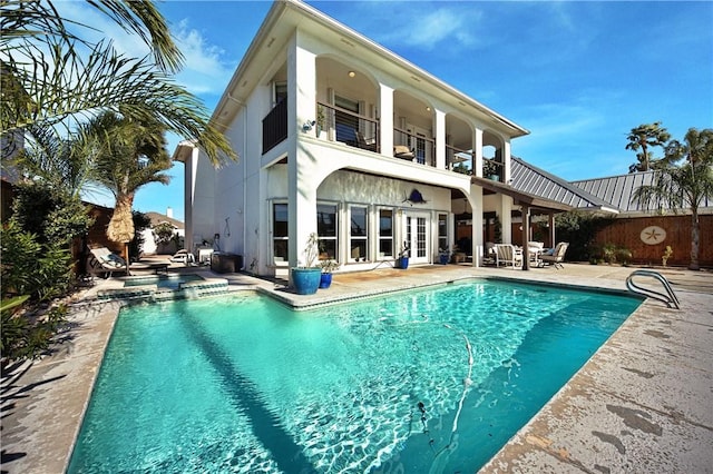 rear view of house with a balcony, fence, stucco siding, french doors, and a patio area