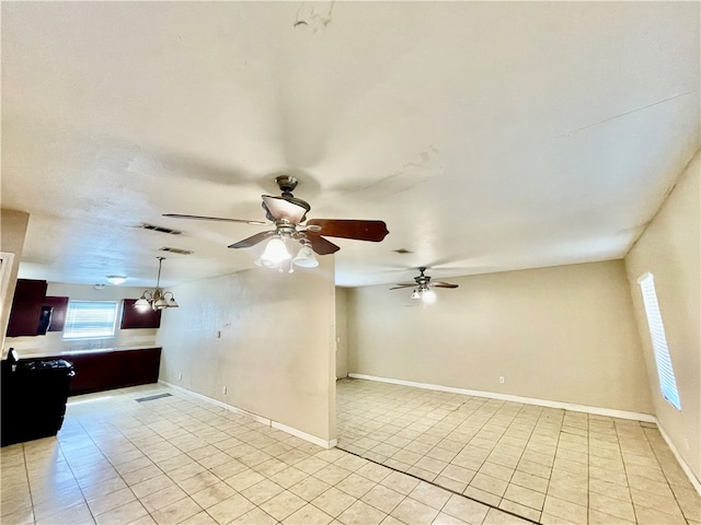 tiled spare room featuring ceiling fan with notable chandelier