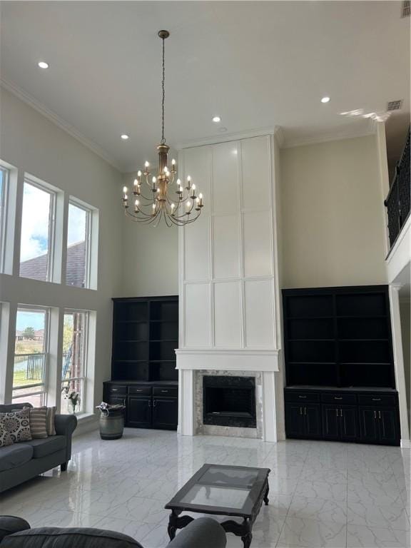 living room with a fireplace, a high ceiling, ornamental molding, and a notable chandelier