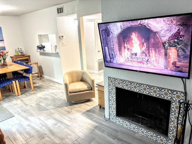 living room featuring wood-type flooring and a tiled fireplace