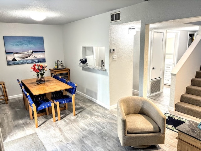 dining area featuring wood-type flooring and a textured ceiling