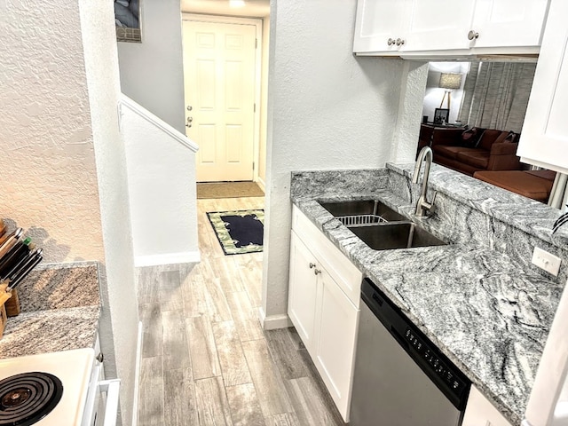 kitchen featuring stainless steel dishwasher, sink, white cabinets, and light stone counters