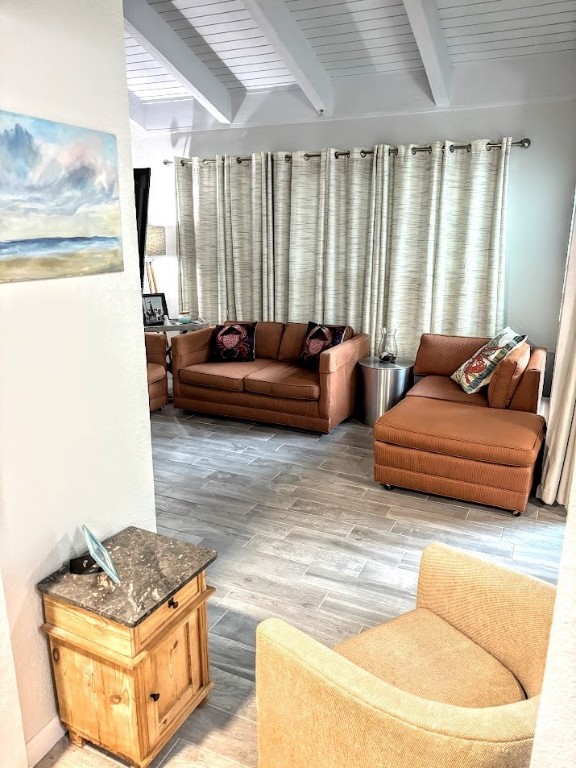 living room featuring beamed ceiling and light wood-type flooring