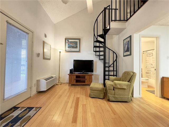 living room featuring a wealth of natural light, light wood-type flooring, high vaulted ceiling, and an AC wall unit