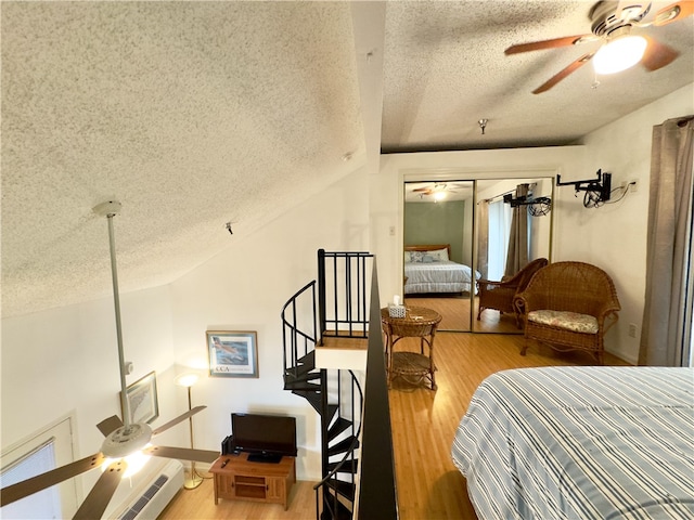 bedroom with hardwood / wood-style floors, vaulted ceiling, ceiling fan, a textured ceiling, and a closet