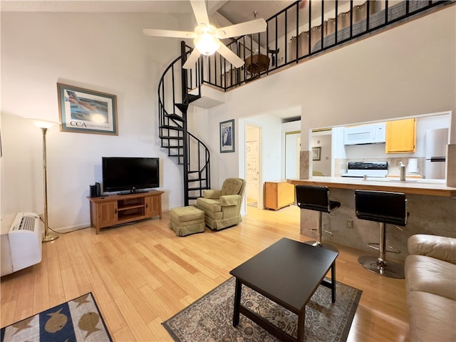 living room featuring ceiling fan, light wood-type flooring, and high vaulted ceiling