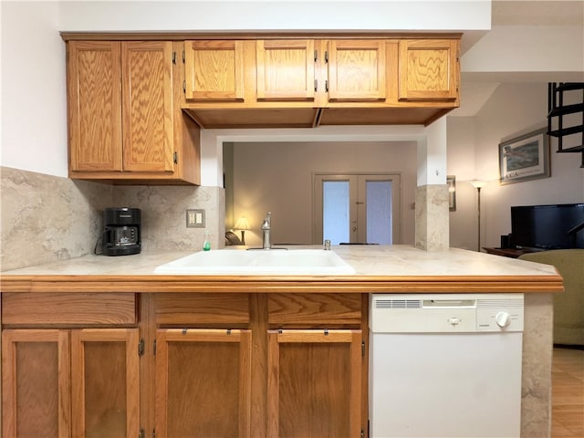 kitchen featuring decorative backsplash, french doors, kitchen peninsula, white dishwasher, and sink