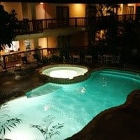 pool at twilight featuring an in ground hot tub