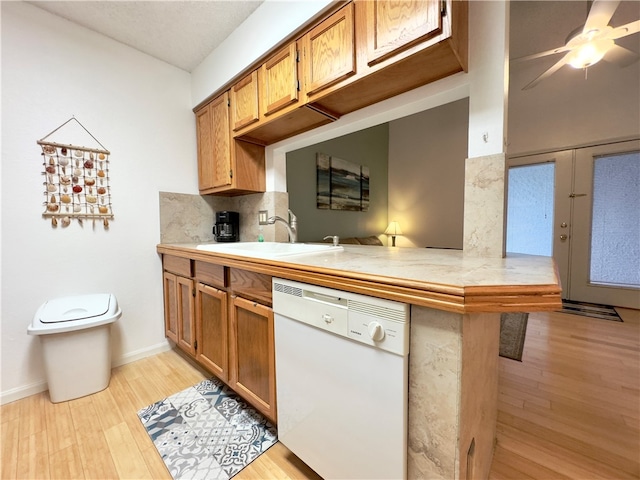 kitchen with dishwasher, tasteful backsplash, kitchen peninsula, light hardwood / wood-style floors, and a breakfast bar