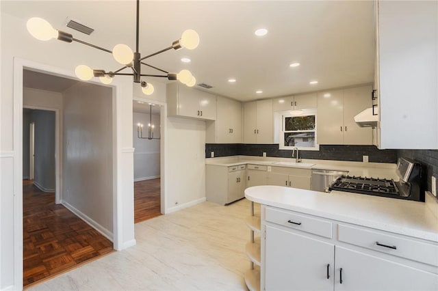 kitchen featuring stove, sink, pendant lighting, and white cabinets