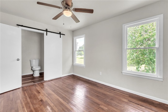 130 N Houston St, Aransas Pass, TX 78336 - spare room featuring baseboards, wood finished floors, a healthy amount of sunlight, and a barn door